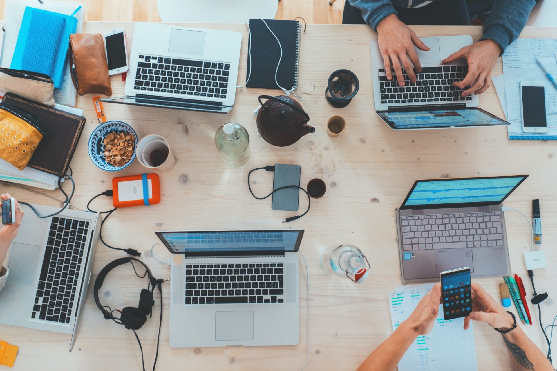 Aerial view looking down on a cluttered table with several laptops and smartphones