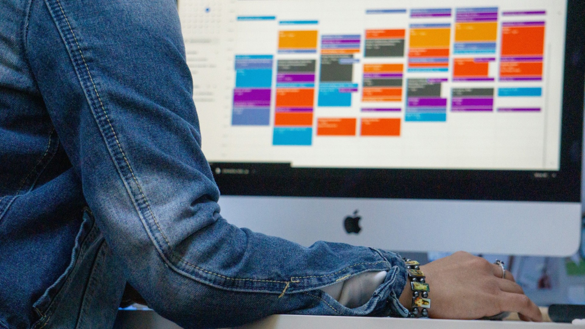 Over-the-shoulder image of a computer monitor displaying a busy calendar