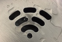Image of the wifi symbol: a dot with lines radiating above it in a cirular pattern. This image shows a black symbol on a grey, metallic background with clear water droplets scattered atop