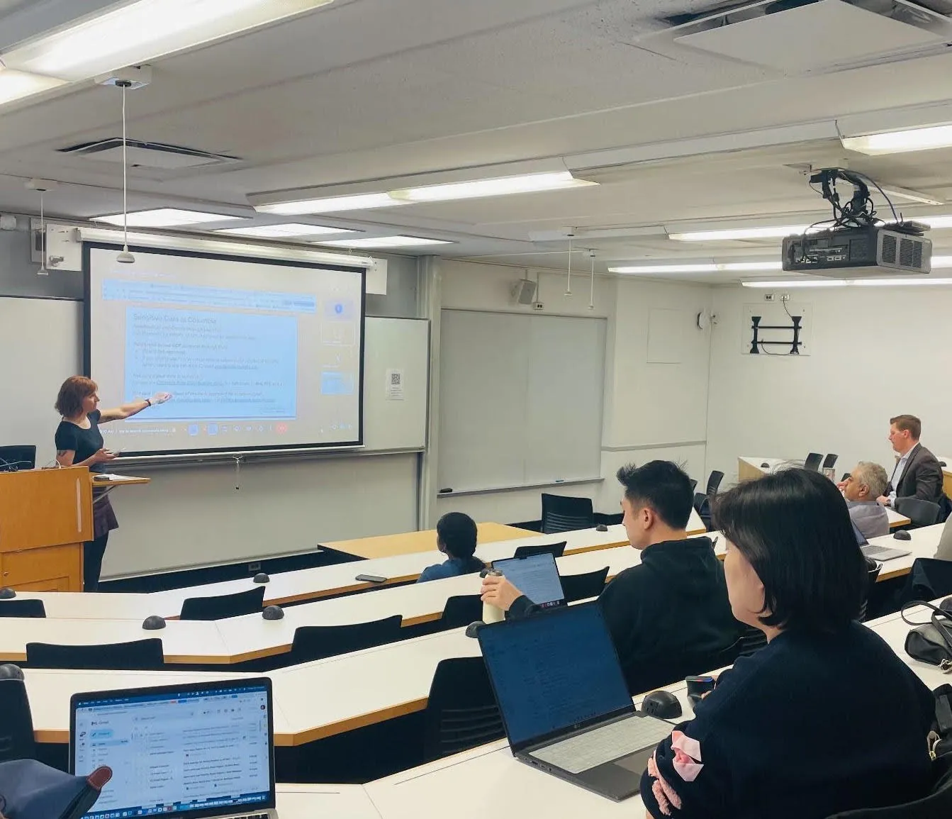 Photo of woman presenting at a podium in a classroom
